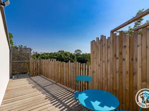 une clôture en bois avec une chaise bleue sur une terrasse dans l'établissement Studio cosy avec terrasse en campagne, proche Nantes - FR-1-622-109, à Saint-Christophe-la-Couperie