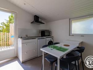 une petite cuisine avec une table et des chaises blanches dans l'établissement Studio cosy avec terrasse en campagne, proche Nantes - FR-1-622-109, à Saint-Christophe-la-Couperie 6 autres photos