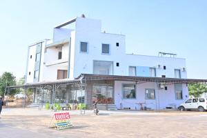 un bâtiment blanc avec un panneau devant dans l'établissement Hotel Rudraksha Restaurant And Resort, à Khātu