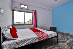 a bedroom with a bed with red pillows and a window at Hotel O HM & Restaurant in Begās