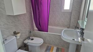 baño con aseo y lavabo con cortina de ducha púrpura en Dominión Park Apartamento, en Cala del Moral 12 fotos más