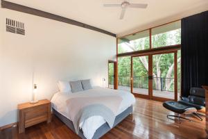 a bedroom with a bed and a chair and windows at Elements - Echuca Holiday Homes in Moama +14 photos