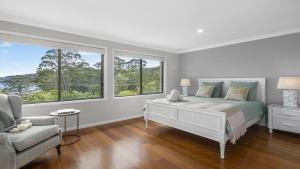 a bedroom with a bed and a couch and windows at 'Bay Dreams at Killcare' by HolidayCo in Killcare