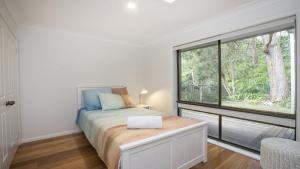 a bedroom with a bed and a large window at 'Bay Dreams at Killcare' by HolidayCo in Killcare