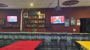 a bar with a red table and chairs and two televisions at H Misión Sayula in Sayula