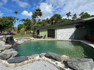 a swimming pool with rocks in front of a house at Jabiru Stay Daintree Village in Daintree