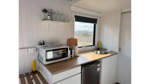 a small kitchen with a microwave and a sink at Little Lady Cabin by Tiny Away in Rylstone +33 photos
