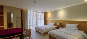 a hotel room with two beds and a window at Phoenix Dragon M.I.C.E Hotel in Kunming