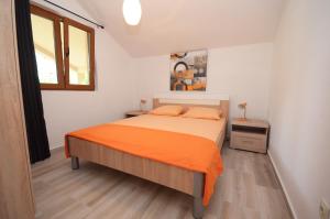 een slaapkamer met een bed met een oranje deken bij Apartmani Mizdrak in Kotor