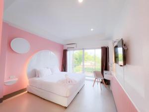 une chambre avec un lit blanc et un mur rose dans l'établissement The Room Hotel, à Ban Nong Puk