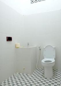 a bathroom with a white toilet and a black and white tile floor at Hotel Wijaya Magelang in Magelang