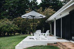 un patio con due sedie e un ombrellone di Coromandel Homestead, Berrima a Berrima