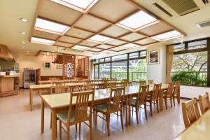a dining room with tables and chairs and windows at Bijintei in Tanabe