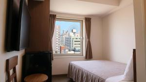 a hotel room with a bed and a window at Swanky Hotel Otomo in Sapporo