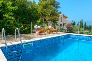 a swimming pool with two chairs and a table next to it at Tandem Apartments with Swimming pool in Cavtat