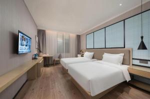 Una habitación de hotel con dos camas y un televisor. en Echarm Hotel Jinan West Station International Exhibition Center, en Jinan 203 fotos más