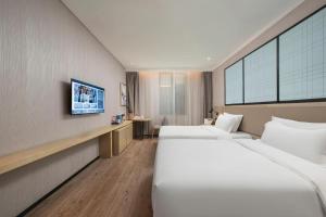 una habitación de hotel con dos camas y un televisor en Echarm Hotel Jinan West Station International Exhibition Center, en Jinan