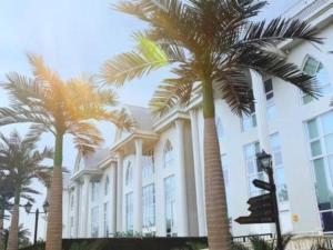 a large building with palm trees in front of it at Xana Hotelle Nanchang Tengwang Pavilion Wanshougong in Nanchang