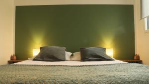 a bed with two pillows and a green wall at maison de vacances locquirec in Locquirec