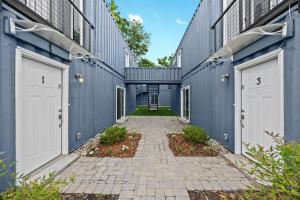 a hallway between two blue buildings with white doors at Experience the Unique Re-Nu Shipping Container #3 in Louisville