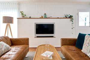 a living room with two brown couches and a fireplace at Sweet Az in Bicheno