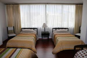 a hotel room with two beds and a window at Hotel 6 De Diciembre in Quito