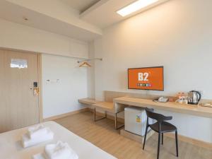 una stanza con una scrivania e un tavolo con un orologio sul muro di B2 Map Ta Phut Boutique & Budget Hotel a Rayong