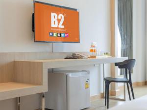 una stanza con una scrivania con una TV a parete di B2 Map Ta Phut Boutique & Budget Hotel a Rayong