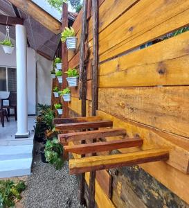 a wooden bench against a wall with potted plants at Salty Palm Villa in Arugam Bay