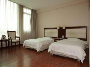 a hotel room with two beds and a chair at Yidun Hotel Foshan Luocun in Foshan