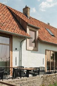 a patio with tables and chairs in front of a house at Hoeve De Hemel in Zuienkerke