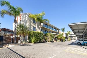 a parking lot in front of a building with palm trees at Beachside Breakaway Glenelg South 200m to the Beach in Glenelg