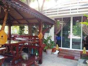a patio with a wooden pergola and a table and bench at Baan Gon Chompu in Suan Phung