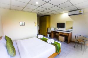 ein Schlafzimmer mit einem Bett und einem Schreibtisch mit einem Computer in der Unterkunft Central Place Hotel in Ban Thai Wat Khot