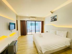 a bedroom with a white bed and a television at Luxsna Residence in Hat Yai