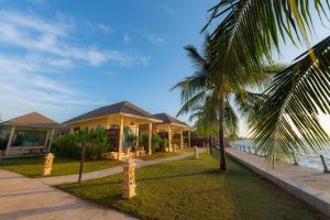 a house with a palm tree in front of the water at Villa Phra Chan Resort in Ban Pak Nam Khem Nu