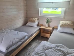 a room with two beds and a window at Domki letniskowe Pastelowe Ustronie in Ustronie Morskie