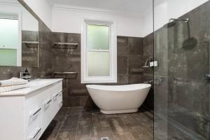un bagno con vasca e doccia in vetro di 'Barton House' - Ideal Location Stroll to CBD a Orange