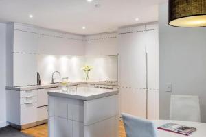 a white kitchen with a sink and a refrigerator at Oaks Queenstown Club Suites in Queenstown +240 photos