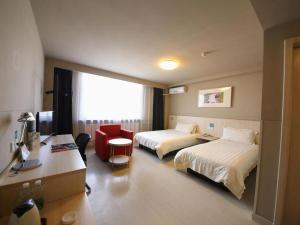 une chambre d'hôtel avec deux lits et un bureau dans l'établissement Jinjiang Inn Tonghua Shengli Road Branch, à Tonghua