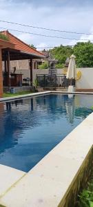 a swimming pool with a table and a umbrella at Simple Homestay Balangan in Jimbaran