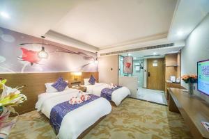 a hotel room with two beds and a television at Xinyuan Hot Spring Hotel in Haikou