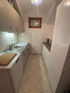Una pequeña cocina con gabinetes blancos y un fregadero. en Appartment with a view in Necujam, en Nečujam