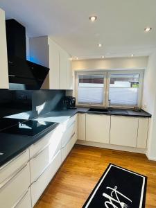 a kitchen with white cabinets and a black counter top at BERGSEERUHE - FeWo Höfats in Nesselwang +3 photos