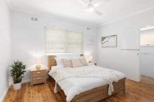 a white bedroom with a bed and a window at Barnhill Beach House - by Coast Hosting in Terrigal +9 photos