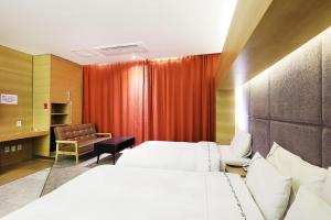 a hotel room with a bed and a red curtain at Business Design Hotel LUV in Incheon