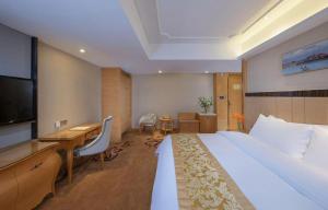 a hotel room with a large bed and a desk at Vienna Classic Hotel Fujian Shishi Jinsheng in Quanzhou