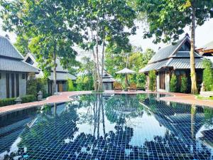 a swimming pool in front of a house at Ruean Racha in Chiang Mai