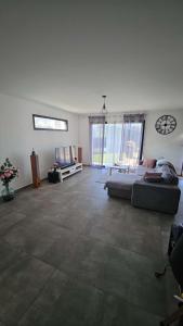 a living room with a couch and a clock on the wall at Chambre spacieuse #2 in Clonas-sur-Varèze