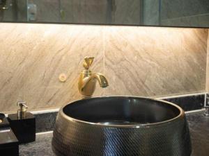 ein Waschbecken mit einem goldenen Wasserhahn in einem Badezimmer in der Unterkunft Zhangjiajie Xiangfu International Hot Springs Hotel in Zhangjiajie + 101 Fotos